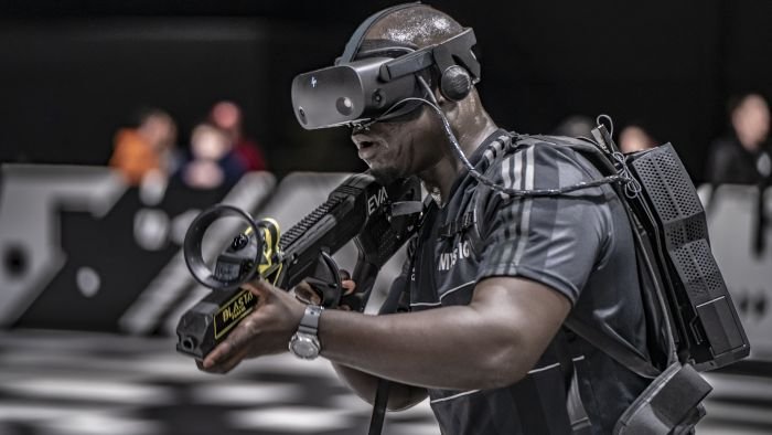 Joueur d'EVA, équipé d'un casque et d'un ordinateur sur le dos, en plein match esport.